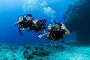 Two divers making an ok sign to the camera along with their dive instructor with chloes diving center